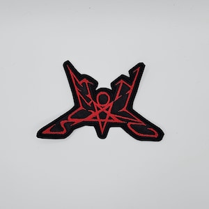 May include: Black and red embroidered patch featuring a stylized pentagram with a central circle and angular lines. The patch has a black border and is set against a white background. The design is symmetrical and bold.