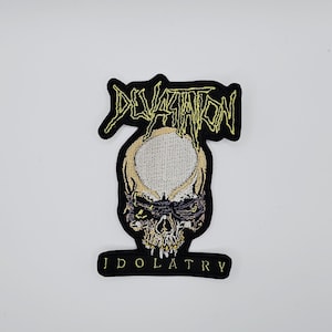 Puede incluir: Parche bordado con un diseño de calavera. La palabra "DEVASTATION" está en texto amarillo estilizado sobre la calavera. La palabra "IDOLATRY" está debajo. El parche tiene un borde negro.