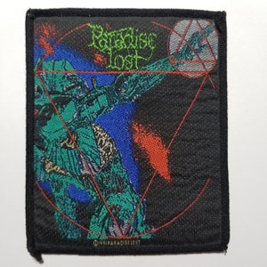 May include: A black woven patch featuring a green, blue and red graphic of a figure within a circle containing a triangle. The text "Paradise Lost" is written in green and white. The text "©1991 PARADISE LOST" is written in gold at the bottom.