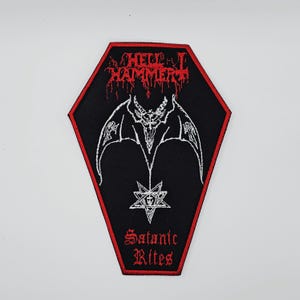 Peut inclure: Écusson noir en forme de cercueil avec bordure rouge. Il présente une créature blanche en forme de chauve-souris avec un pentagramme et les mots "HELLHAMMER" et "Satanic Rites" en rouge, en lettres gothiques.