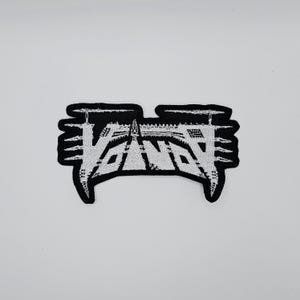 May include: A black and white embroidered patch with the word "VANT" in a stylized, gothic font. The patch has a black border and is set against a white background. The design is symmetrical and bold.