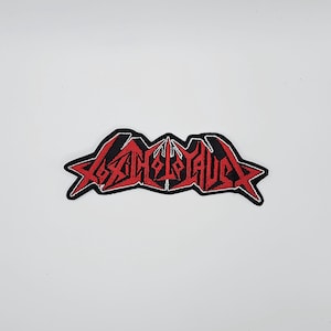May include: Embroidered patch with the word "ASPHYXIA" in red, stylized, gothic lettering. The patch has a black border and is set against a white background. The patch is likely for a jacket or bag.