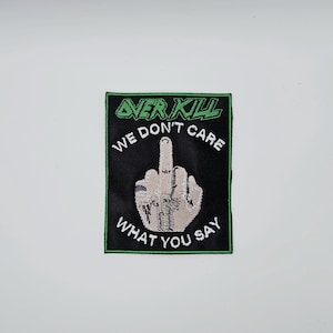 May include: Black patch with a green border featuring the text "OVER KILL" and a hand giving the middle finger. The text "WE DON'T CARE WHAT YOU SAY" is below the hand.