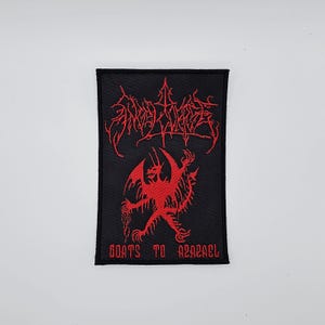 May include: Black rectangular patch with red embroidered text and imagery. The top text is stylized and difficult to read. Below is a red illustration of a horned demon holding chains. The text "GOATS TO AZAZEL" is at the bottom.