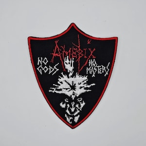 Op de afbeelding: Zwart schildvormig embleem met een rode rand. Het embleem toont de bandnaam "Amebix" in rood, samen met de zinnen "No Gods" en "No Masters" in wit. Een witte afbeelding staat in het midden.