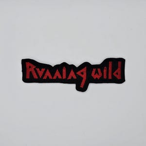 May include: Black embroidered patch with the words "Running Wild" in red, stylized lettering. The patch has a black border and is likely designed to be sewn or ironed onto clothing or accessories.