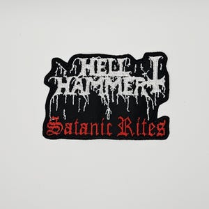 May include: A black embroidered patch featuring the white text HELLHAMMER in a jagged, dripping font style. Below the main text, the words Satanic Rites are embroidered in a bold red gothic-style font. The patch has a black border.