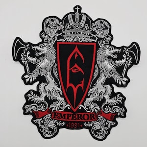 May include: Embroidered patch featuring a black shield with a red border and a stylized emblem. Two white lion-like creatures flank the shield, holding instruments. The word "EMPEROR" is on a red banner, with "1991" below.
