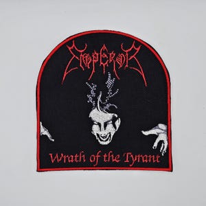 Peut inclure: Écusson noir avec texte et motif brodés en rouge. Le mot "Emperor" est en haut, avec un visage stylisé et des mains en dessous. Le texte "Wrath of the Tyrant" est en bas, le tout dans une arche bordée de rouge.