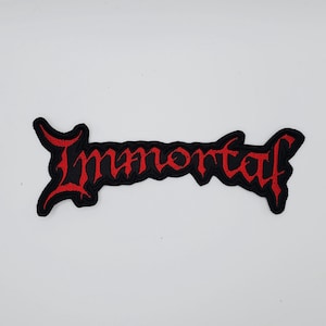 May include: Black embroidered patch with the word "Immortal" in red, stylized lettering. The patch has a jagged, irregular border. The design is likely for a band or music-related merchandise.