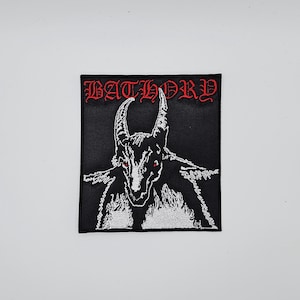 May include: Black square patch featuring a white illustration of a horned creature with red eyes. The word "BATHORY" is embroidered in red at the top. The patch is likely for clothing or accessories.