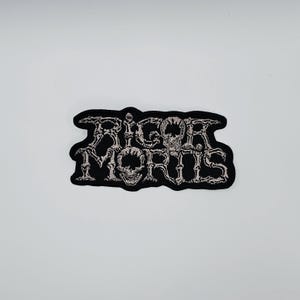 Rigor Mortis-logotypformad kantbroderad lapp