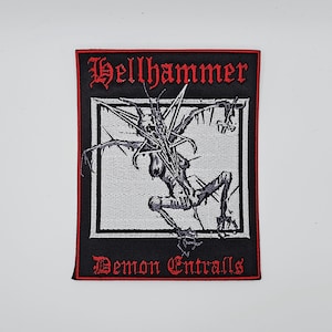 Puede incluir: Parche rectangular negro con ribete rojo y texto. El texto superior dice "Hellhammer" en fuente gótica. El centro presenta una ilustración en blanco y negro de una figura esquelética. El texto inferior dice "Demon Entrails".
