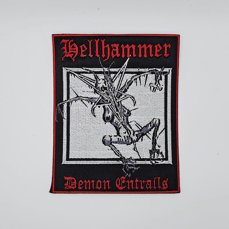 K&ouml;nnte beinhalten: Rechteckiger schwarzer Aufn&auml;her mit roter Umrandung und Text. Der obere Text lautet "Hellhammer" in gotischer Schrift. In der Mitte befindet sich eine schwarz-graue Illustration einer skelettartigen Figur. Der untere Text lautet "Demon Entrails".