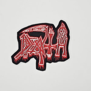 Könnte beinhalten: Gestickter Aufnäher mit dem Wort "DEATH" in gotischer Schrift, einer Sense und einem Sensenmann-Design. Der Aufnäher ist schwarz mit roten und weißen Details, ideal für Jacken oder Taschen.