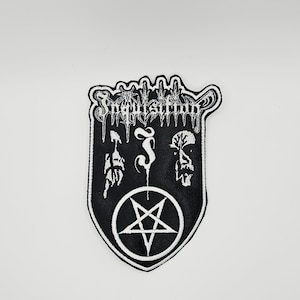 Op de afbeelding: Een zwart-witte geborduurde patch met de tekst Inquisition in een gestileerd lettertype aan de bovenkant. Onder de tekst staan twee abstracte figuren naast een centrale letter J, met een groot pentagram in een cirkel onderaan.