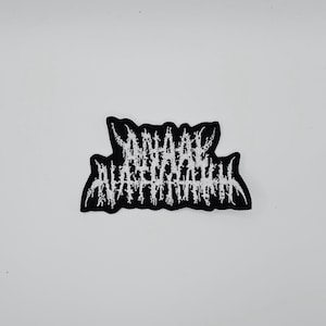 May include: Black and white embroidered patch with the text "Dahmer - A Serial Killer". The patch has a jagged, distressed font style. The patch is on a white background.