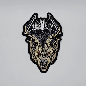 May include: Embroidered patch featuring a demonic creature with red eyes, sharp teeth, and horns. The patch has the word "Niefheim" in a gothic font. The design is primarily black, gold, and white, with a bat-like shape at the top.