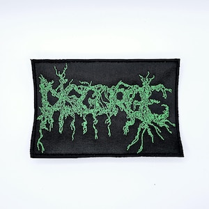 May include: Black rectangular patch with green embroidered text that reads "DEGRADE" in a stylized, organic font. The patch has a black border and is set against a white background. The green text has a dripping, vine-like appearance.