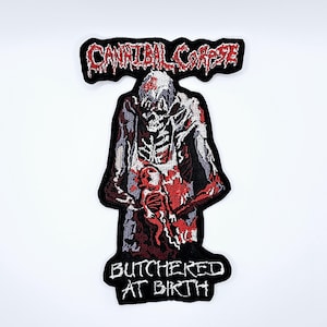 Op de afbeelding: Geborduurde patch met de tekst "CANNIBAL CORPSE" in rood en wit, boven een gruwelijke figuur die een baby vasthoudt. De tekst "BUTCHERED AT BIRTH" staat eronder. De patch is zwart met rode, witte en grijze details.