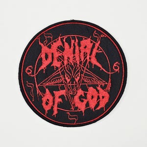 May include: Round black patch with a red pentagram design and the words "DENIAL OF GOD" in a gothic font. The patch features a goat head within the pentagram and a red border.
