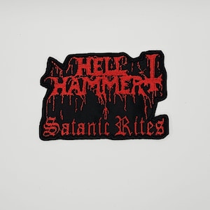 以下が含まれることがあります： 黒い刺繍ワッペン。上部には滴るようなスタイルの赤い文字で「HELLHAMMER」、その下にはゴシック調の赤い文字で「Satanic Rites」と刺繍されており、全体が黒い布地の背景に配置されています。
