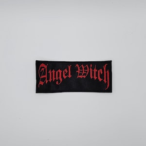 Könnte beinhalten: Ein schwarzer, rechteckiger Aufnäher mit dem in roter gotischer Schrift gestickten Schriftzug "Angel Witch". Der Aufnäher ist wahrscheinlich aus Stoff und zum Aufnähen oder Aufbügeln auf Kleidung oder Accessoires geeignet.