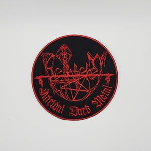 Può includere: Una toppa rotonda nera con ricami rossi. Il design include un pentagramma e le parole "Suicidal Dark Metal" in carattere gotico. Sono presenti anche lettere stilizzate aggiuntive. Per abbigliamento.