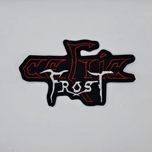 Könnte beinhalten: Schwarzer Aufnäher mit dem Text "CELTIC FROST" in Weiß und Rot. Der Aufnäher hat einen schwarzen Hintergrund mit roter Umrandung. Der Text ist in einer stilisierten, gotischen Schriftart.