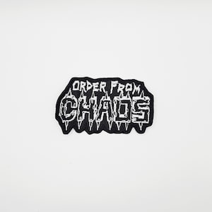 以下が含まれることがあります： 白文字で「ORDER FROM CHAOS」と書かれた黒色の刺繍パッチ。パッチはギザギザの縁取りがあり、衣類やアクセサリーに縫い付けたり、アイロンで接着したりするように設計されています。