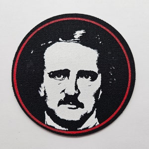 May include: A black and white embroidered patch of Edgar Allan Poe's face with a red circular border.