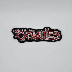 Casualties-logotyp med röd och vit kant och broderad lapp