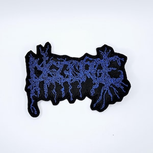 May include: Black embroidered patch with the word "DEATHCORE" in blue, stylized, dripping font. The patch has a black background and a jagged edge. The patch is likely for a jacket or bag.