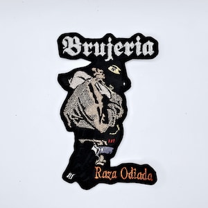 May include: Black embroidered patch with the word "Brujeria" in white gothic lettering. The patch features a detailed illustration of a figure and the words "Raza Odiada" in orange.