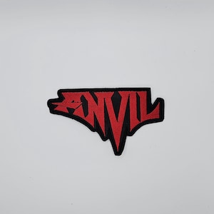 May include: Embroidered patch featuring the word "ANVIL" in red, stylized lettering. The patch has a black border and is set against a white background. The design is bold and eye-catching, suitable for jackets or bags.