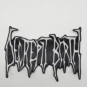 May include: Black and white patch with the text "SECRET BIRTH" in a stylized, gothic font. The patch has a black background with white lettering and a white border. The design has a dripping effect.