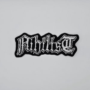 Könnte beinhalten: Schwarz-weißer gestickter Aufnäher mit dem Wort "Philist" in gotischer Schrift. Der Aufnäher hat einen schwarzen Rand und eine rechteckige Form. Der Text ist in weißem Faden.
