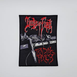 May include: Black embroidered patch with red text and a graphic illustration. The text reads "Deeds of Flesh" above and "Trading Pieces" below. The illustration depicts a skeletal figure. The patch is rectangular.