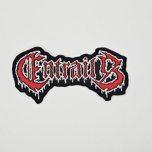 Può includere: Toppa ricamata con la scritta "Entrails" in rosso, lettering stilizzato con contorno bianco, su sfondo nero. La toppa ha un bordo frastagliato e un effetto gocciolante sulle lettere.