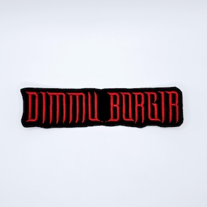 Peut inclure: Écusson rectangulaire noir avec le texte rouge "DIMMU BORGIR" en police gothique. L'écusson a une bordure cousue et est posé sur un fond blanc. Idéal pour les vêtements ou les accessoires.