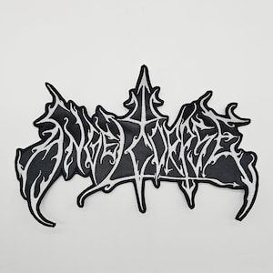 May include: A black and white embroidered patch featuring the word "INNERSPHERE" in a gothic font. The patch has a black background with white stitching. The design is in the shape of a stylized leaf, with intricate detailing.
