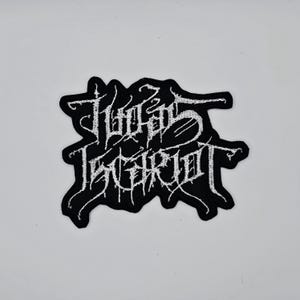 May include: Black and white embroidered patch featuring the words "THROES OF ESCAPISM" in a gothic font. The patch has a black background and white stitching, with a unique, stylized design.