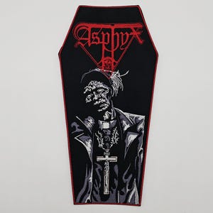May include: Black coffin-shaped patch with a red border. The patch features the word "Asphyx" in red gothic lettering above a black and white illustration of a figure wearing a cross pendant.