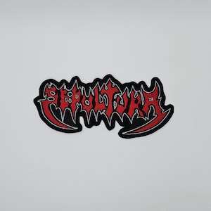 Könnte beinhalten: Ein roter und schwarzer gestickter Aufnäher mit dem Wort "SEPULTAR" in gotischer Schrift. Der Aufnäher hat einen schwarzen Rand mit roten Nähten und befindet sich vor einem weißen Hintergrund. Geeignet für Kleidung oder Accessoires.