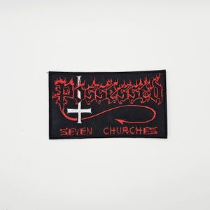 May include: Black rectangular patch with red and white text. The word "Possessed" is written in a stylized font above a white inverted cross. Below the cross is a red arrow and the words "Seven Churches".