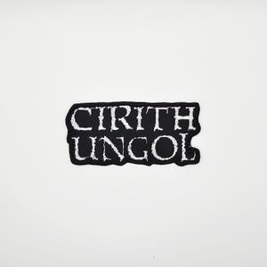 Może przedstawiać: Czarno-biała naszywka z napisem "CIRITH UNGOL". Naszywka ma czarne tło z białymi literami i czarną obwódką. Naszywka ma kształt prostokąta.