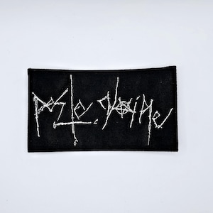 Può includere: Toppa rettangolare nera con testo bianco ricamato. Il testo è in stile gotico. La toppa è probabilmente per abbigliamento o accessori.