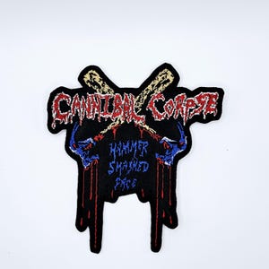 May include: Black embroidered patch featuring the band name "Cannibal Corpse" in red and white, with the text "Hammer Smashed Face" in blue. The design includes crossed baseball bats and dripping blood details.