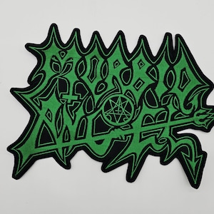 May include: A green and black embroidered patch with a stylized design. The patch features a jagged outline and intricate lettering, along with a pentagram and trident. The design is in bright green against a black background.