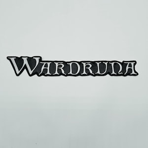 May include: A rectangular embroidered patch featuring the word WARDRUNA in a stylised, serif font. The lettering is white with a thin black outline, set against a solid black background that follows the contour of the text characters.
